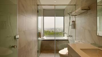 A modern bathroom with a glass-enclosed shower, a large mirror, and a view of a cityscape.