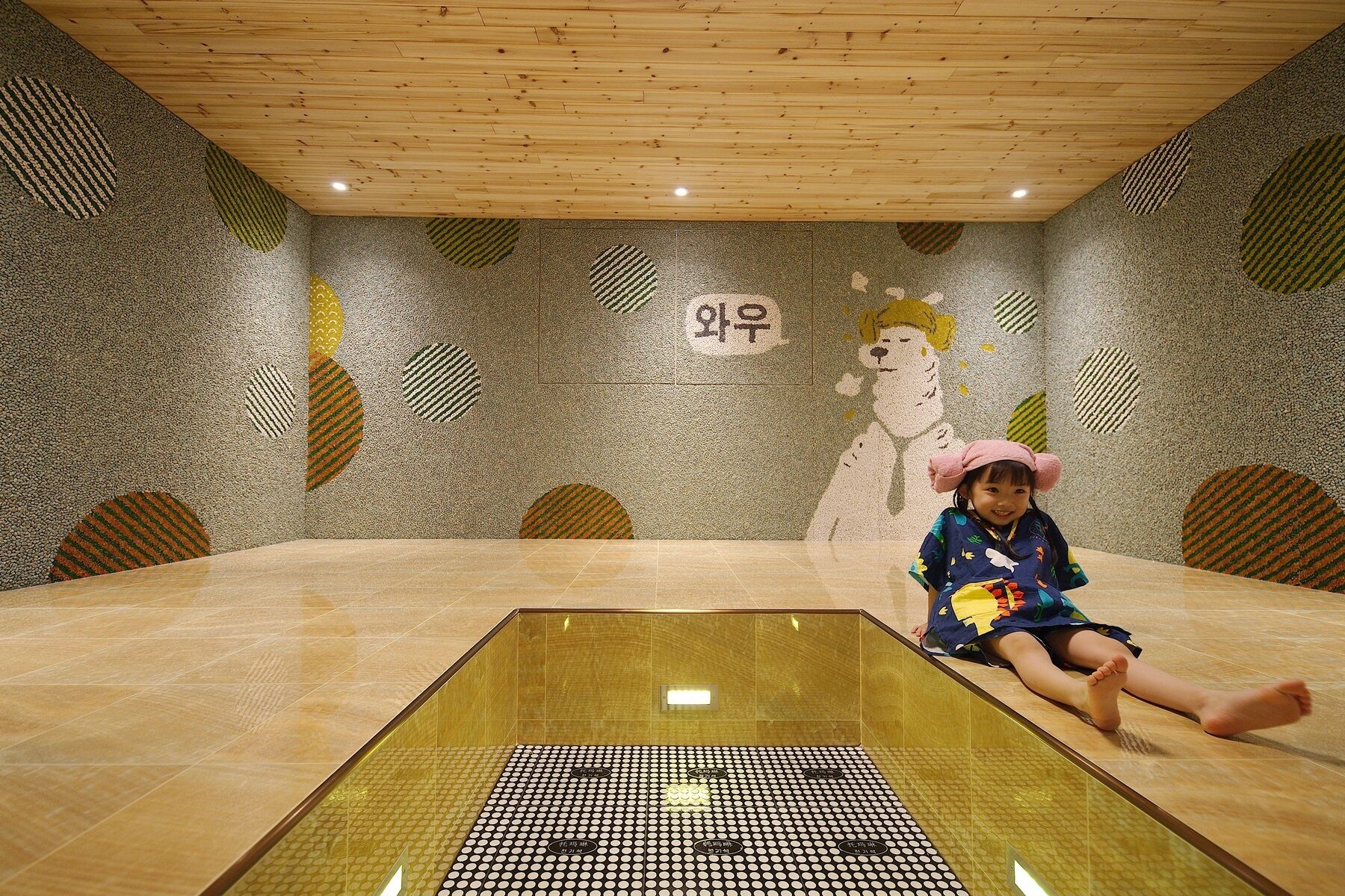 A room with a wooden ceiling, a tiled floor, and a wall with circular patterns and a cartoon character.