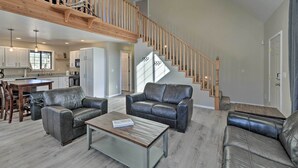 Ein großzügiger Wohnbereich mit Ledersofas, einem Holztisch und einer Treppe mit Holzwertungen.