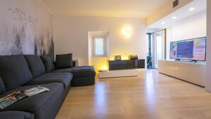 Een moderne woonkamer met een hoekbank, een flatscreen televisie en een wandgemonteerde televisie.