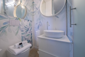 A modern bathroom with a round mirror, a white sink, and a towel rack.