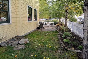A yellow building with a stone pathway leading to a white fence.