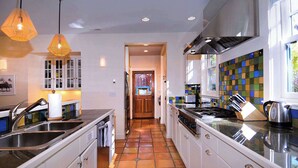 A modern kitchen with white cabinets, a tiled backsplash, stainless steel appliances, and pendant lighting.