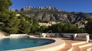 A swimming pool with a view of a mountainous landscape and buildings in the background.