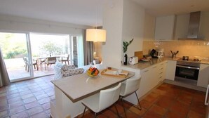 A modern kitchen with a central island, white cabinetry, and a dining area with a table and chairs.