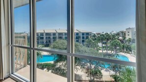 A view from a window overlooking a pool area with a building in the background.