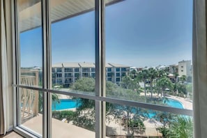Vista da janela sobre a área da piscina, com um edifício ao fundo.