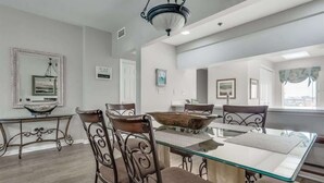 A dining area with a glass table, metal chairs, a decorative bowl, and a chandelier.