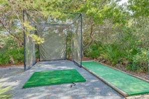Un terrain de tennis entouré d’un filet, avec un tapis vert au centre et un tapis vert sur le côté.
