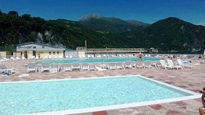 A pool area with lounge chairs and a building in the background. - Residenza Menaggio - Glicine (Menaggio)