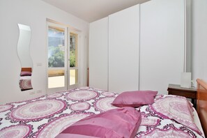 A bedroom with a bed, a large mirror, a sliding door to a balcony, and a nightstand. - Residenza Menaggio - Glicine (Menaggio)