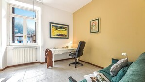 Una habitación con escritorio, silla y sofá verde con una revista.