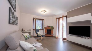 A living room with a sofa, a television, a fireplace, and a window. - Menaggio Palphi (Menaggio)