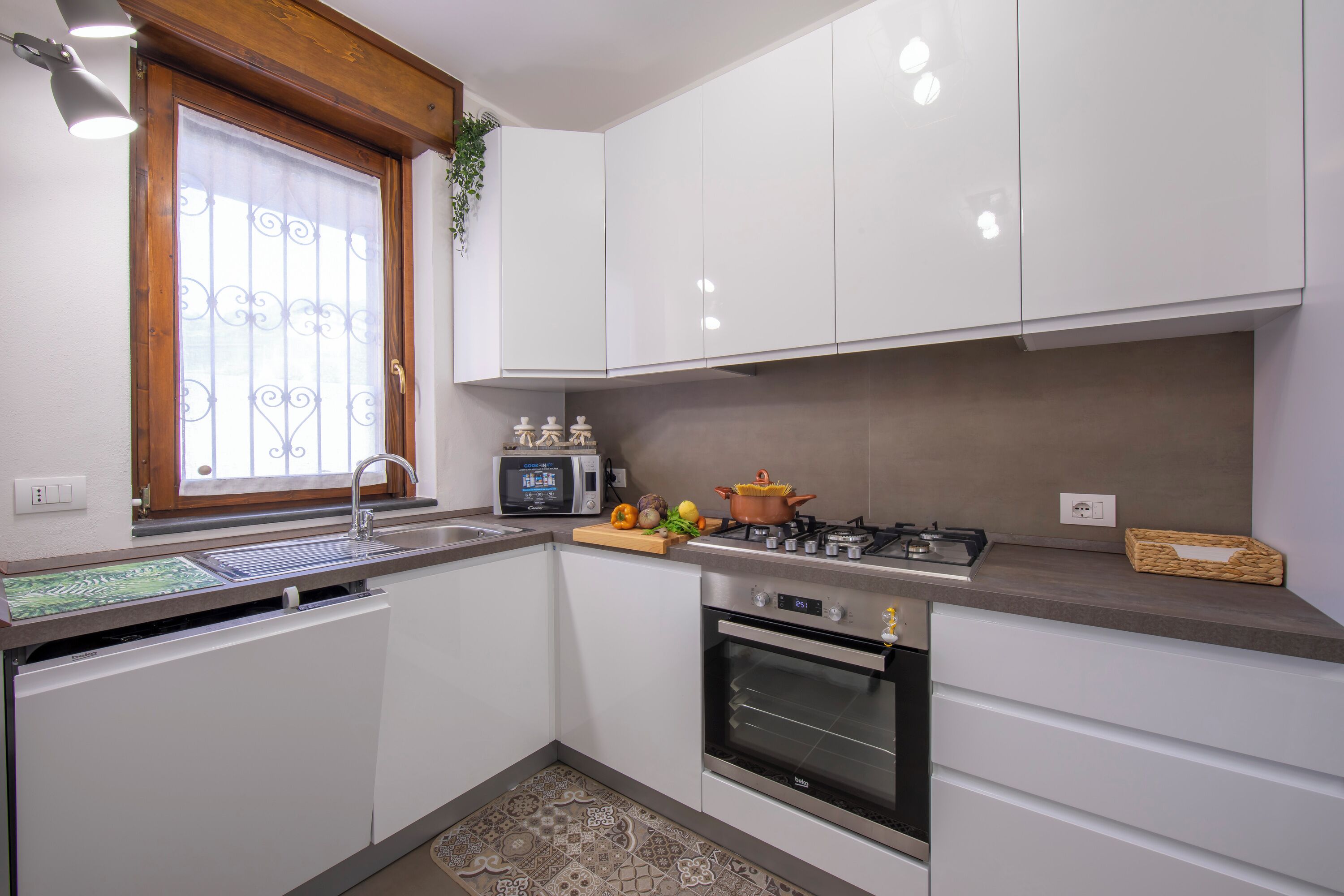 A kitchen with white cabinets, a microwave, a stove, and a window with a decorative iron grill.