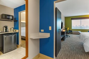 Une chambre d’hôtel équipée d’une kitchenette, d’un lit, d’un bureau et offrant une vue sur la ville.