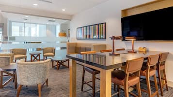 A modern conference room with a glass partition, wooden furniture, and a large flat-screen TV.