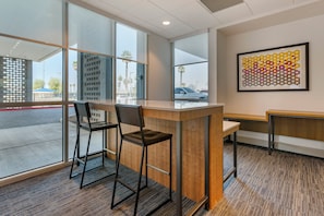 Un intérieur moderne avec un bar, des espaces pour s’asseoir et une grande fenêtre donnant sur la rue.