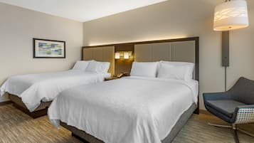 Habitación de hotel con dos camas, un escritorio, una silla, una lámpara y un cuadro en la pared.