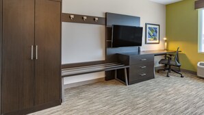 A modern hotel room with a large wardrobe, a flat-screen TV mounted on the wall, a desk with drawers, a chair, and a framed picture on the wall. - Holiday Inn Express & Suites Phoenix Dwtn - State Capitol by IHG (Phoenix)
