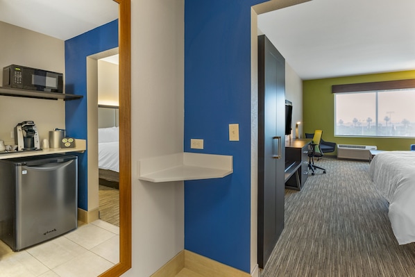 Ein Hotelzimmer mit Küchenzeile, einem Bett, einem Schreibtisch und Blick auf die Stadt.