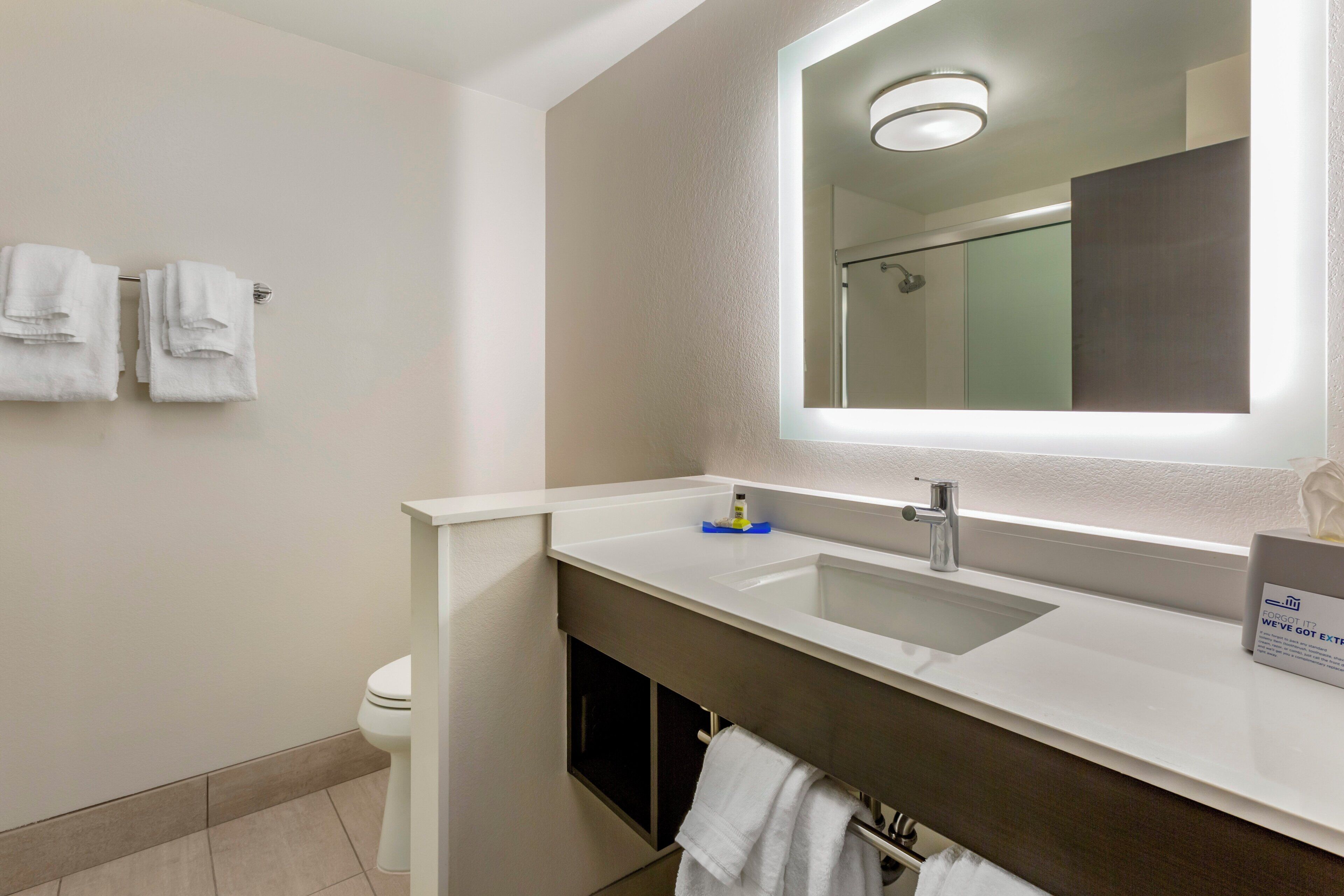 A modern bathroom with a white sink, a mirror, and a toilet.