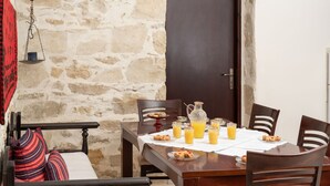 Une table à manger dressée avec des aliments pour le petit-déjeuner, une carafe et des verres de jus d’orange.