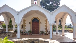 Une cour avec une fontaine en pierre, des arches blanches et une porte en bois.