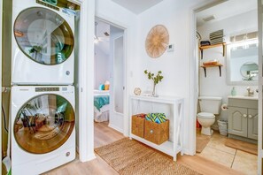 Pesuhuoneessa on kaksi Whirlpool-merkkiä olevaa pesukonetta, pieni käytävä, joka johtaa makuuhuoneeseen, sekä kylpyhuone, jossa on wc, pesuallas ja peili.