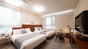 A hotel room with two beds, a desk with a chair, a television, and a small table with a lamp. - Hotel Dm (Seoul)