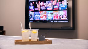 A tray with two glasses of iced drinks and a smartphone charging on a bed. - Hotel Dm (Seoul)
