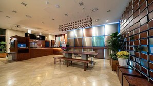 A reception area with a wooden reception desk, a bench, and a wall with a patterned design. - Hotel Dm (Seoul)