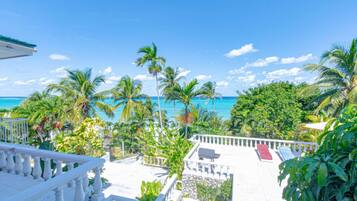 A balcony with a view of the ocean and palm trees.