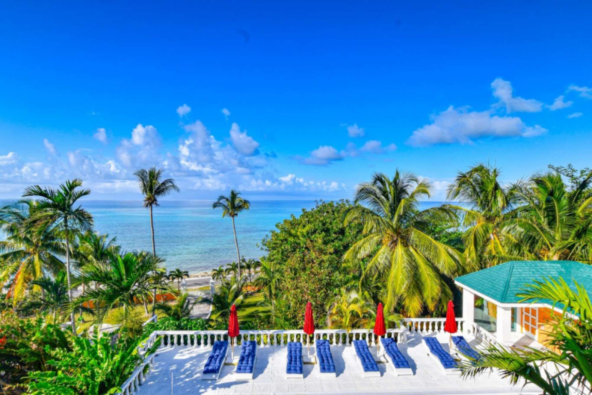 A resort with a pool area, lounge chairs, and a view of the ocean.