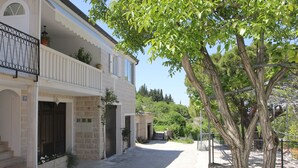 A two-story building with a balcony, a stone facade, and a paved courtyard. - Holiday House Pine Tree (Nerezise)