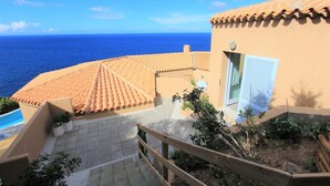 A coastal building with a tiled roof, a wooden staircase, and a view of the sea. - Exclusive clifftop villa in the heart of Gallura with infinity pool (Trinità d'Agultu e Vignola)