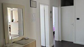 A hallway with a wooden cabinet, a mirror, and a framed certificate on the wall.