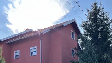 A red building with multiple windows and a paved driveway.