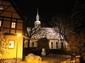 Stunning church with a prominent steeple and beautiful windows, set amidst snow-covered trees.