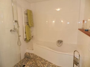 Un baño con bañera, ducha y toallero.