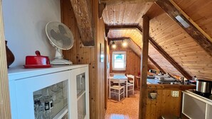 A cozy attic bedroom with a wooden ceiling, a small dining area, and a kitchenette. - Apartment Baberowski 105 - Baberowski, Regina (Insel Poel)