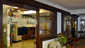 A reception area with a glass door, a clock, and a sign that reads "Pleasant Boulevard." - Pleasant Boulevard MG Road (Bengaluru)