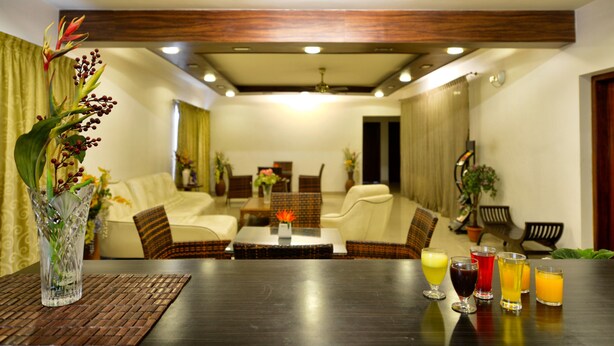 A modern living room with a dark wooden table, seating, and a decorative plant. - Pleasant Boulevard MG Road (Bengaluru)