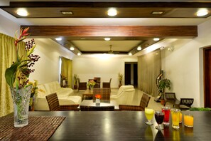 A modern living room with a dark wooden table, seating, and a decorative plant. - Pleasant Boulevard MG Road (Bengaluru)