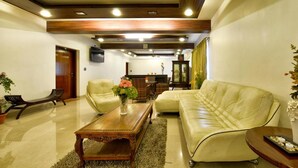 A living room with a sofa, armchairs, a coffee table, and a television. - Pleasant Boulevard MG Road (Bengaluru)