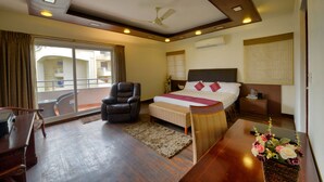 A hotel room with a bed, a chair, a desk, and a balcony with a view. - Pleasant Boulevard MG Road (Bengaluru)