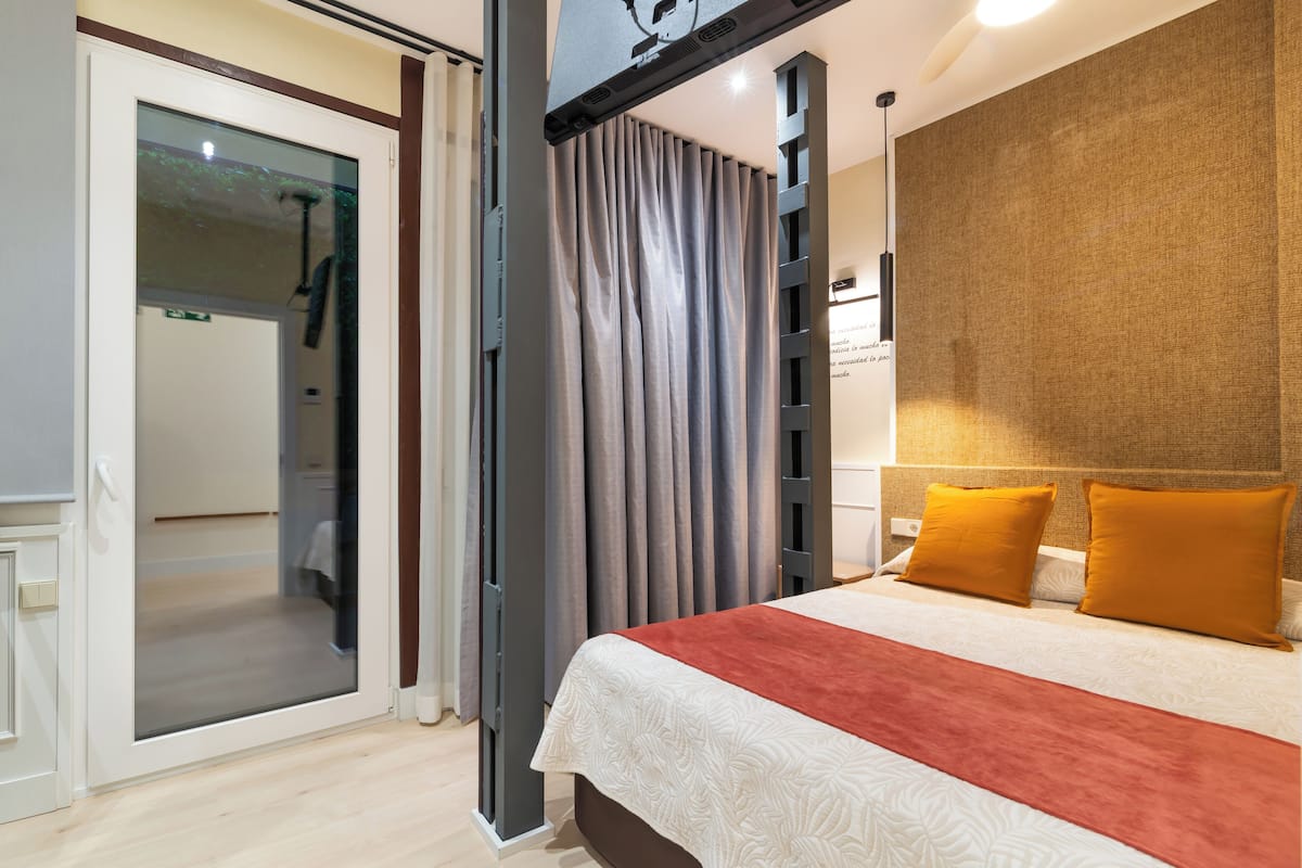 A modern hotel room with a large bed, a sliding glass door leading to a bathroom, and a textured wall.
