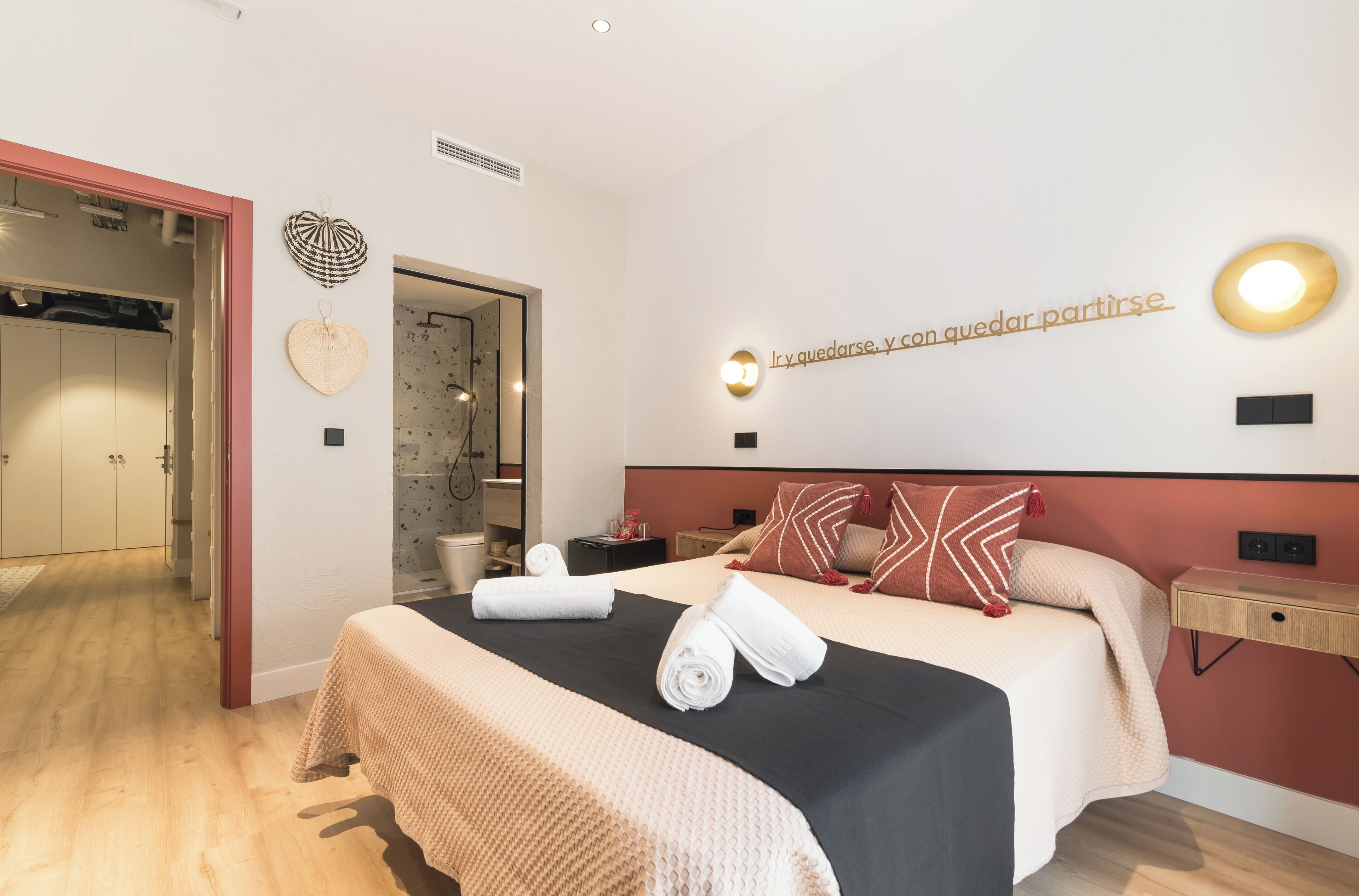 Una habitación de hotel con una cama, una mesita de noche, una lámpara de pared y un adorno en la pared.