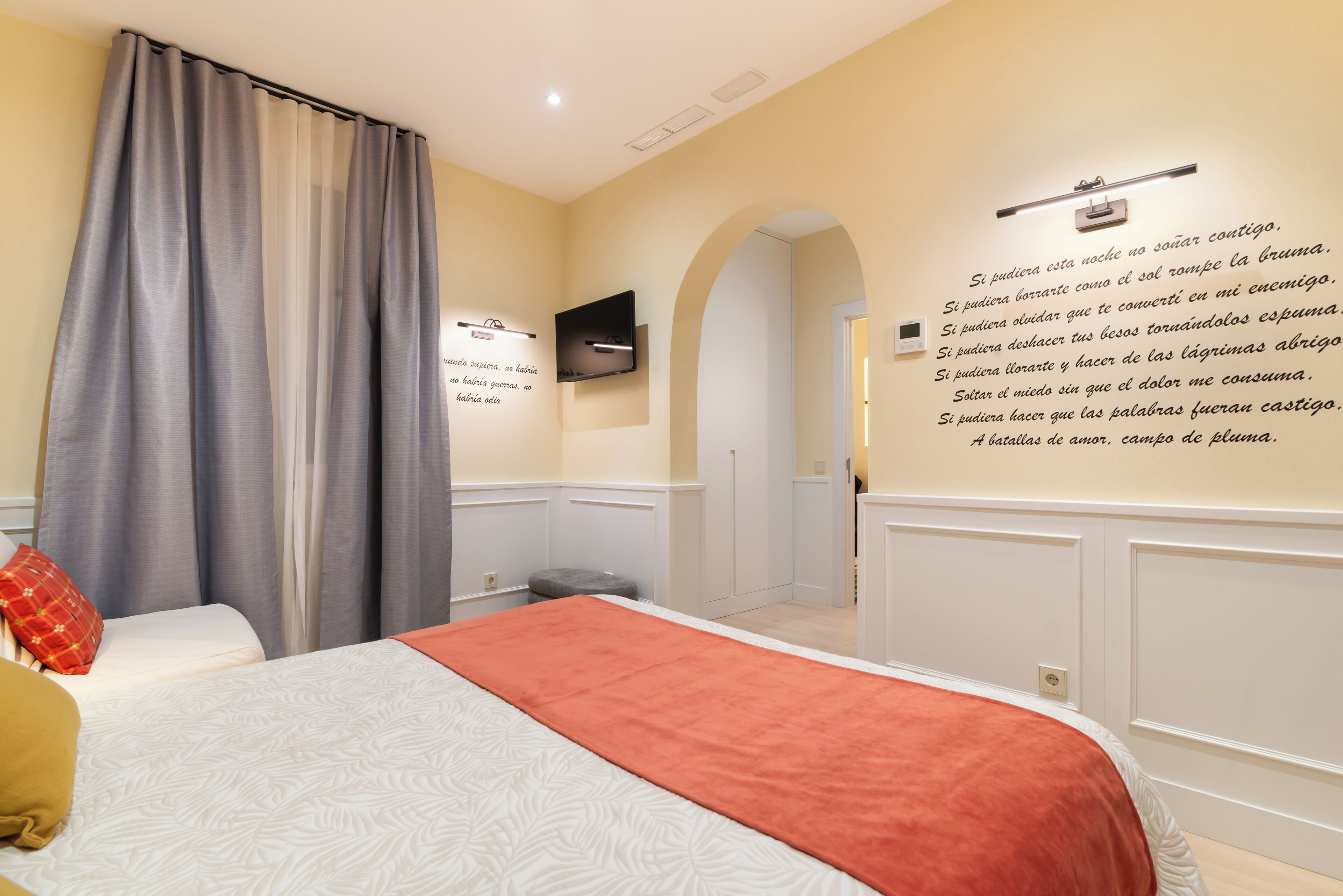 Een hotelkamer met een bed, een aan de muur bevestigde televisie en een bericht op de muur.