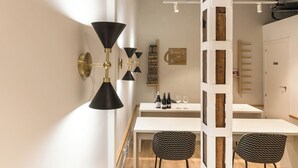 A modern dining area with a white table, black patterned chairs, and a black and gold wall-mounted light fixture. - Cálamo Guesthouse (Madrid)