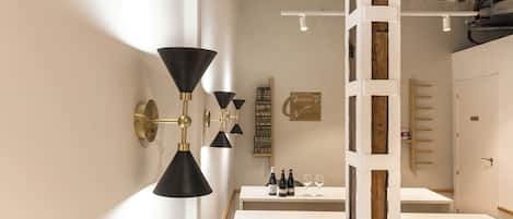 A modern dining area with a white table, black patterned chairs, and a black and gold wall-mounted light fixture.